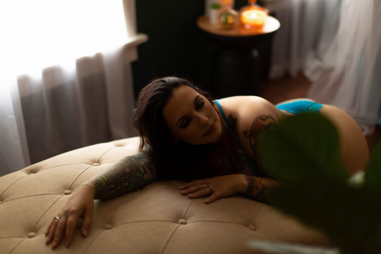 Woman in green lingerie stretches out over a chaise during a classic boudoir photography session with Boudoir by Cipriani