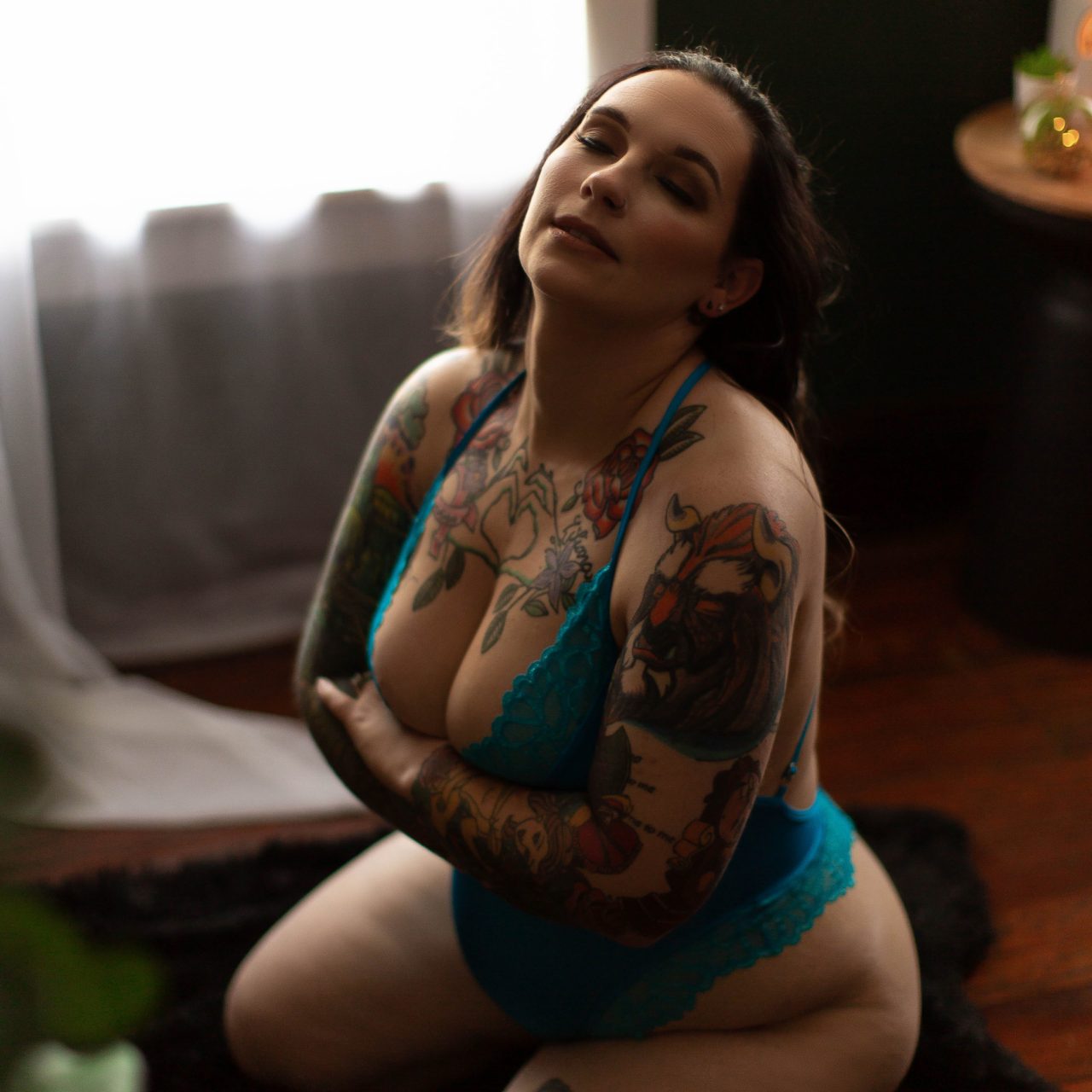 Woman in a green bodysuit with tattoos poses for a classic boudoir photography session with Boudoir by Cipriani