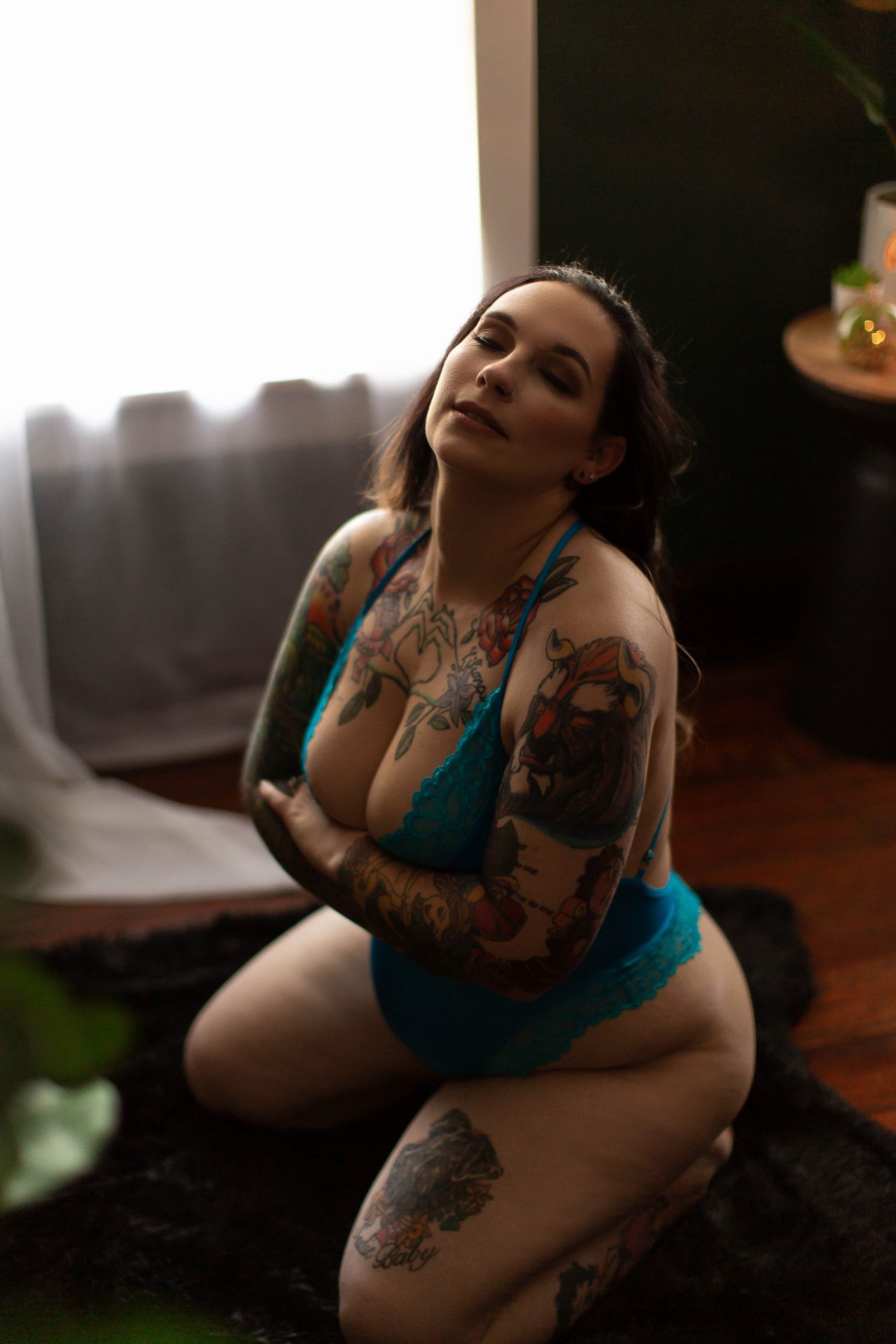 Woman in a green bodysuit with tattoos poses for a classic boudoir photography session with Boudoir by Cipriani