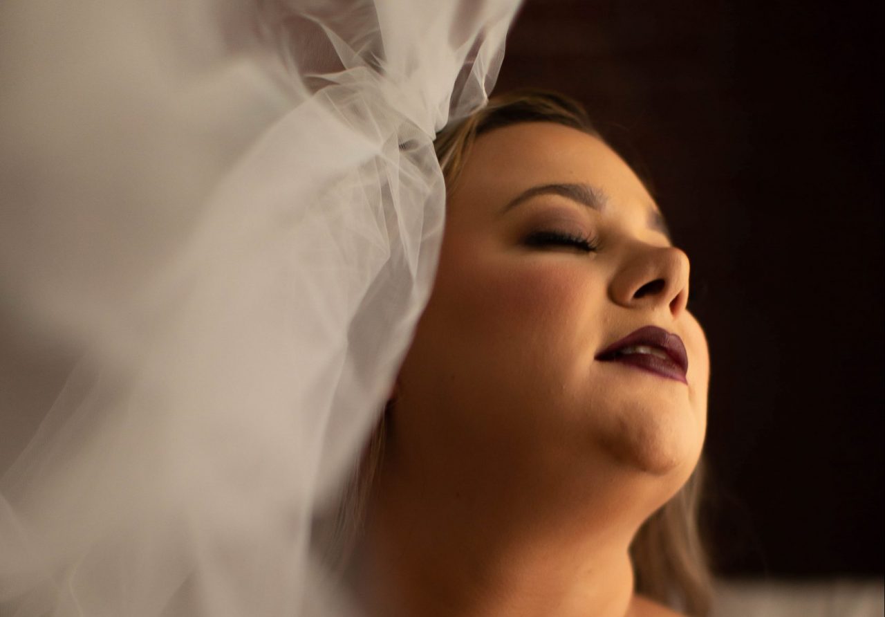 Plus size model reclines on a bed during a wedding boudoir photography session with Boudoir by Ciprani in Tampa, FL